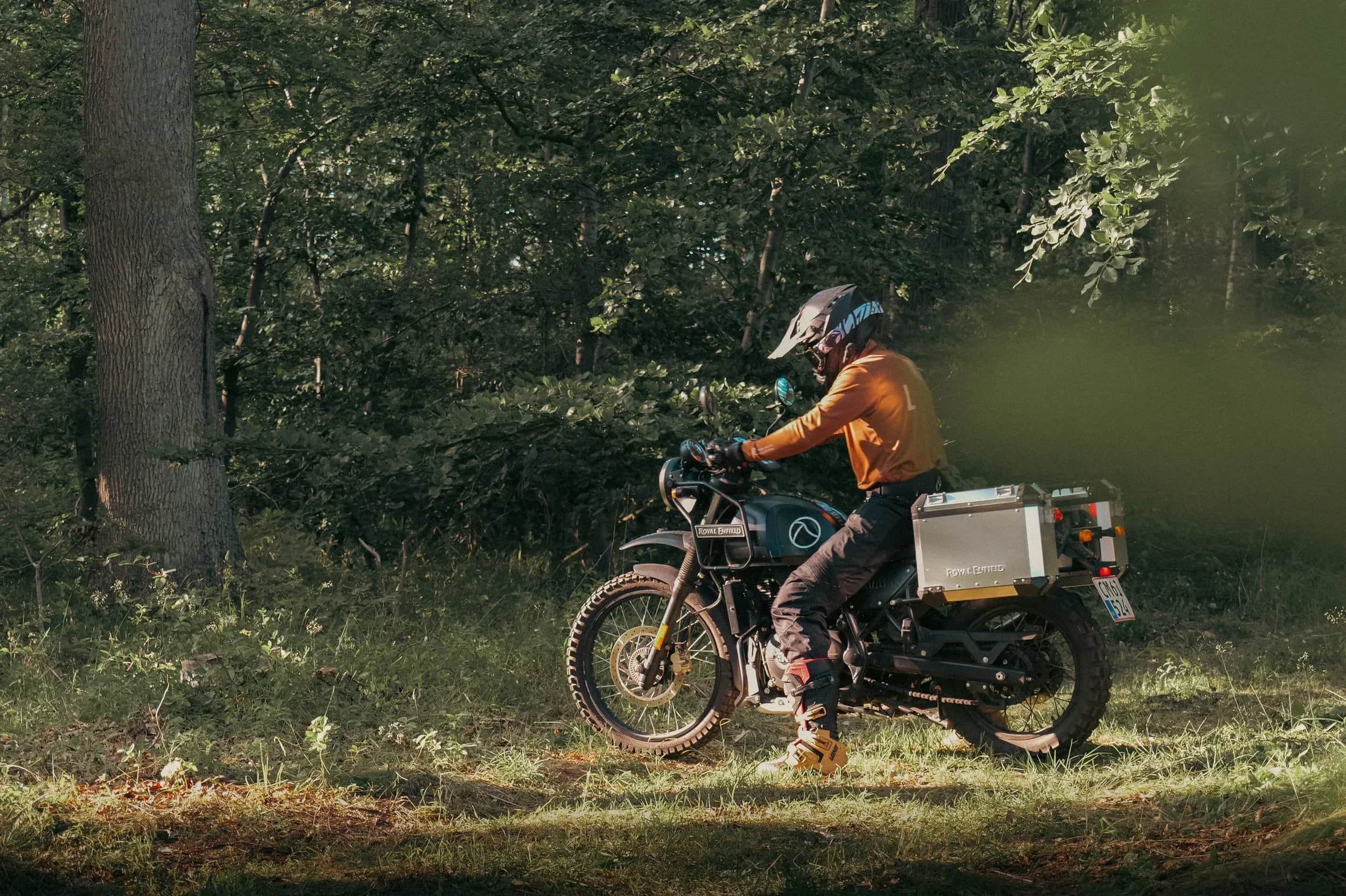 Person kører på en motorcykel ad en skovsti.