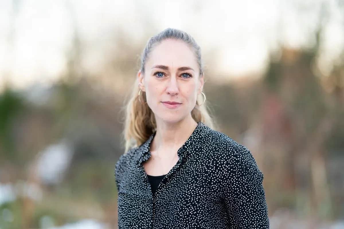 Portræt af en kvinde med lyst hår i en mørk prikket skjorte.